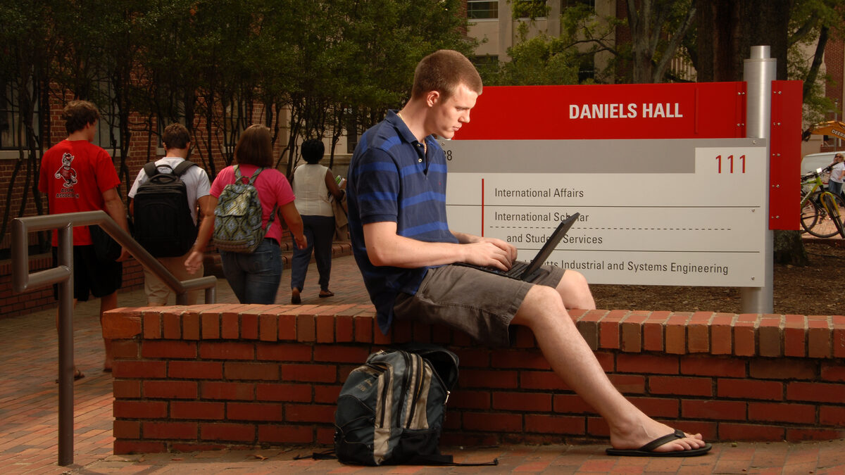 Before heading inside for class, an ISE student works on his computer in front of Daniels Hall.