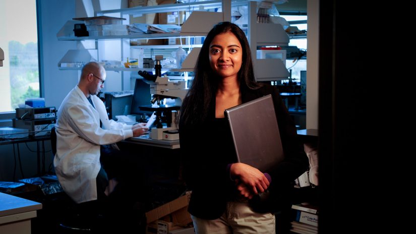 A bme graduate student in engineering stands in front of a lab.